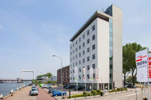 Kantoorgebouw aan de Laan der Verenigde Naties in Dordrecht met uitzicht op de rivier en een brug op de achtergrond.